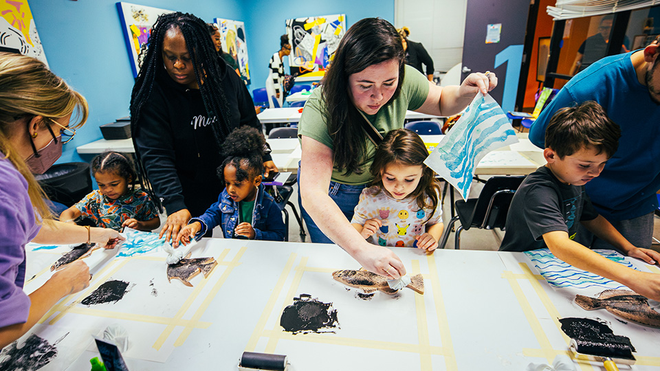 Children and adults at a table painting