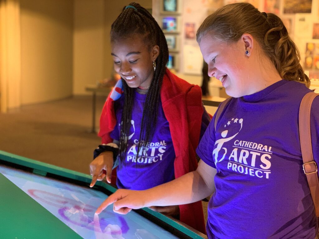 Two students interact with touch screen at art museum